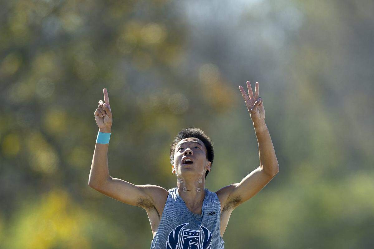 Thomas Nelson’s Riku Sugie gestures as he wins the Class 2A boys state cross country meet at the Kentucky Horse Park on Saturday.