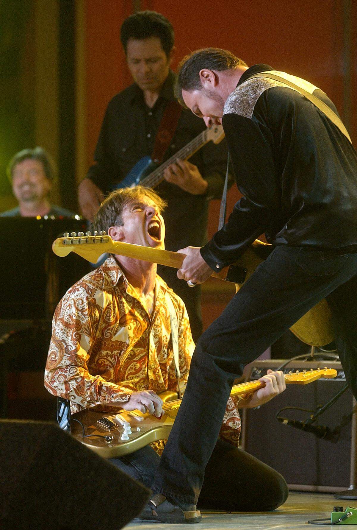 Actor-musician Dennis Quaid, left, interacts with guitarist Jamie James, of The Sharks during the taping of their performance as part of “American Bandstand’s 50th . . . A Celebration,” Friday, April 19, 2002, in Pasadena, Calif.