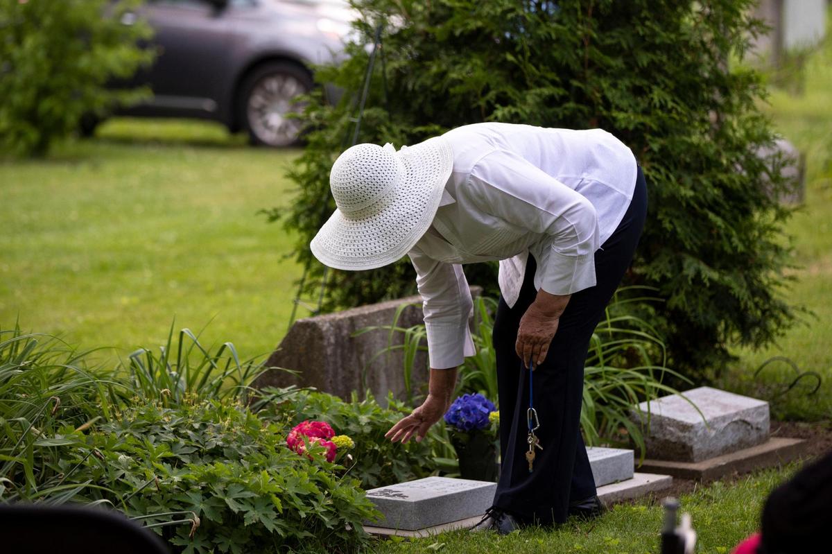 Yvonne Giles places flowers at the memorial markers of Ann Scott and Henry Dunham before a dedication ceremony at African Cemetery #2 in Lexington, Ky., Saturday, May 21, 2022.