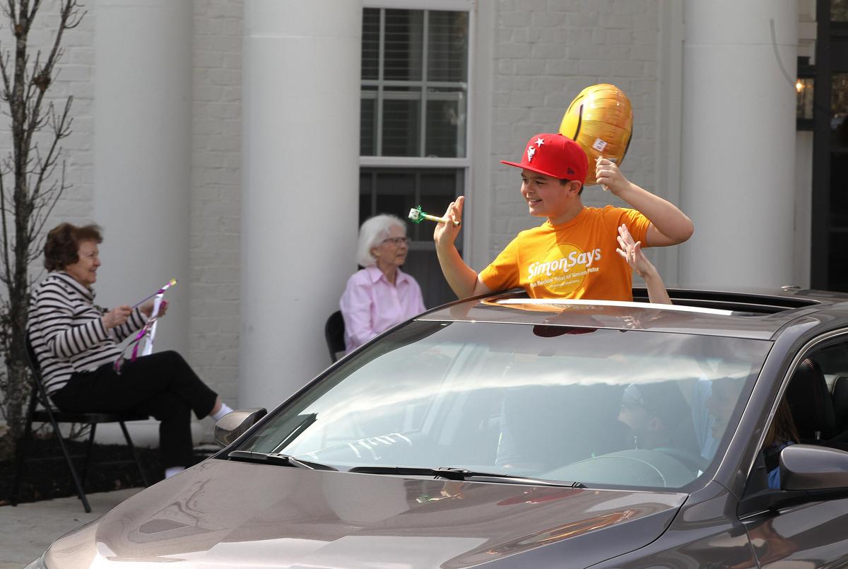 A boy waved to residents as members of Immanuel Baptist Church staged a drive by parade Friday for residents of Highgrove at Tates Creek senior living community.