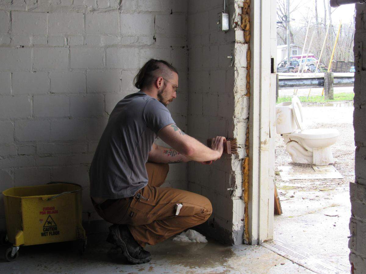 Anthony Saat works on March 25, 2021 to clean up an office for a tattoo parlor in downtown Beattyville, Ky., following disastrous flooding March 1.