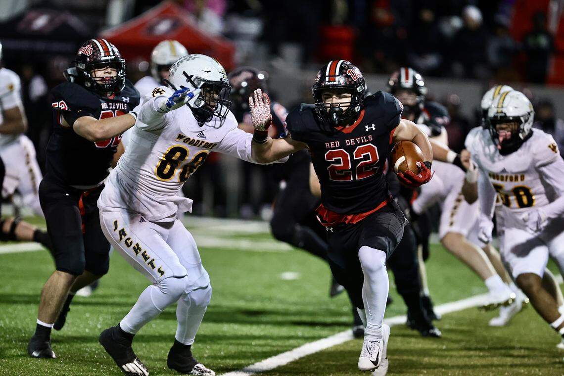 Owensboro’s Evan Hampton (22) broke through Woodford County’s defensive line and eluded Yellow Jackets’ defender Josiah McKee (88) in the Red Devils’ 49-6 win in the Class 5A state football semifinals at Rash Stadium in Owensboro on Friday.