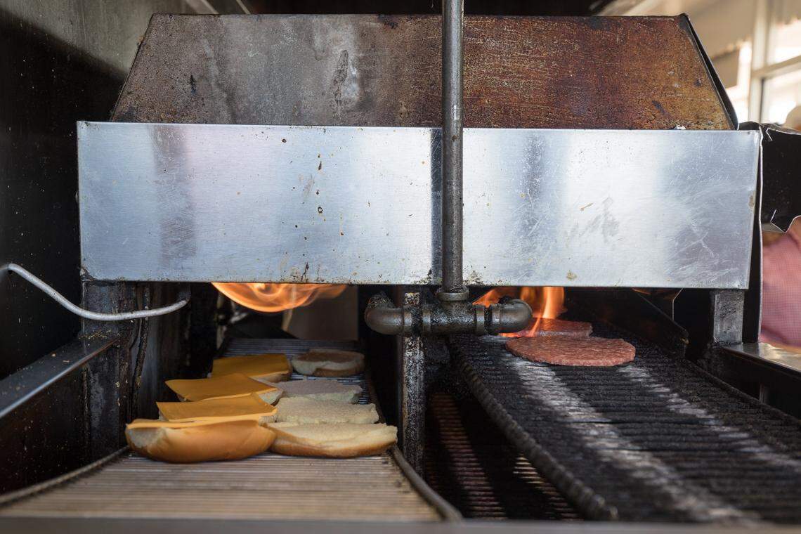 Burgers get cooked under a flame at Burgers Shakes on New Circle Road.