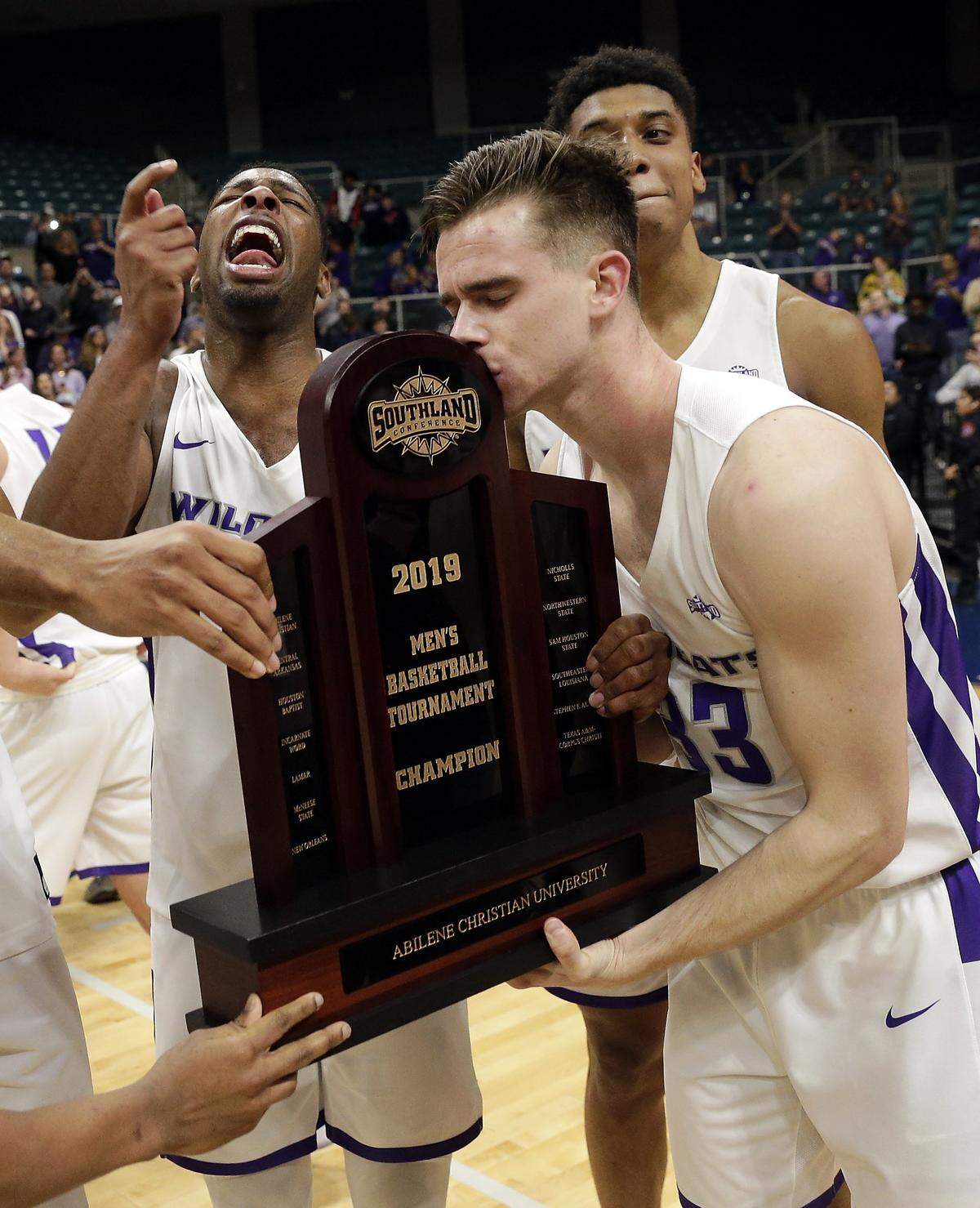 Abilene Christian guard Jaylen Franklin, left, yelled as guard Paul Hiepler (33) kissed the championship trophy after the Wildcats beat New Orleans to claim the Southland Conference Tournament championship and an automatic bid to the NCAA tourney. Kentucky and Abilene Christian have never played each other before..
