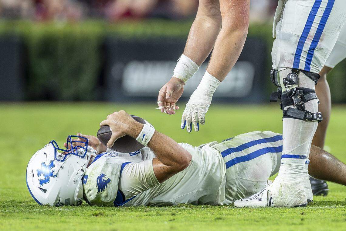 Kentucky offensive lineman Jager Burton (62) reaches down to help up quarterback Cutter Boley (8) after Boley was sacked during Saturday’s game against South Carolina at Williams-Brice Stadium in Columbia, S.C.