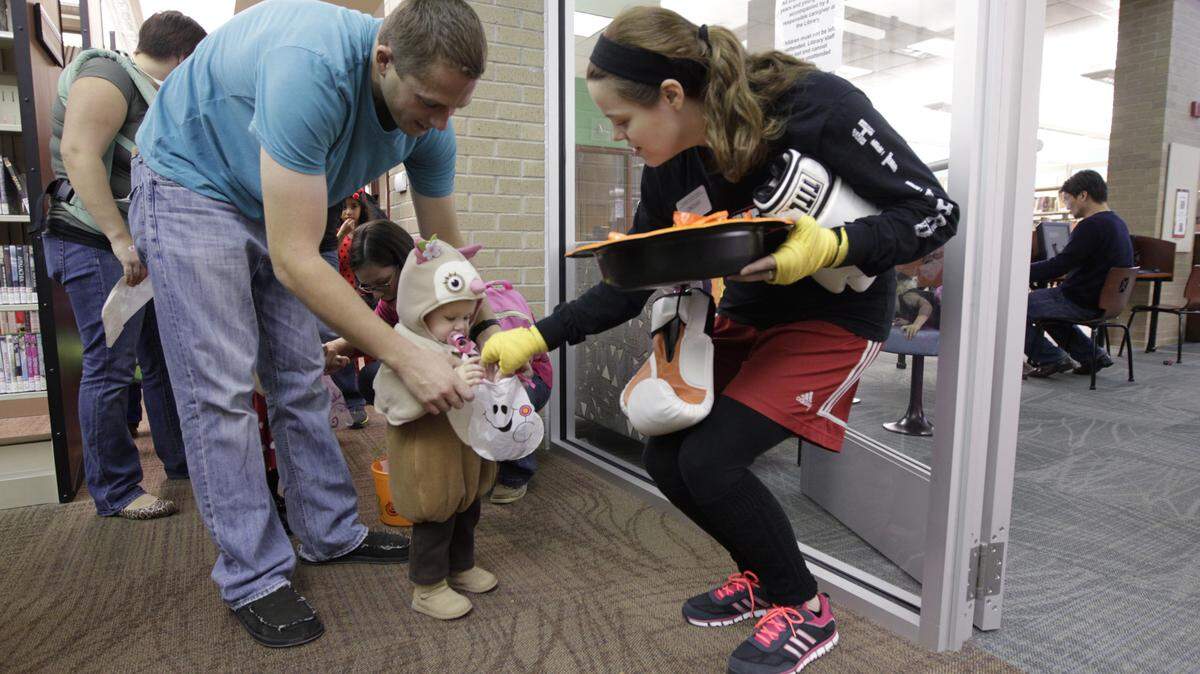 Patrick Sumner and daughter, Isa Sumner, age 14 months trick or treated with librarian assistant Lindsay Warnick during Boo Bash at the Beaumont Branch of the Lexington Public Library in Lexington, Ky., on Oct. 30, 2013. The indoor event had a trick or treat parade and activities and snacks for children 0-6. Rainy weather is expected during trick or treating hours on Halloween night.  Photo by Pablo Alcala | Staff 
