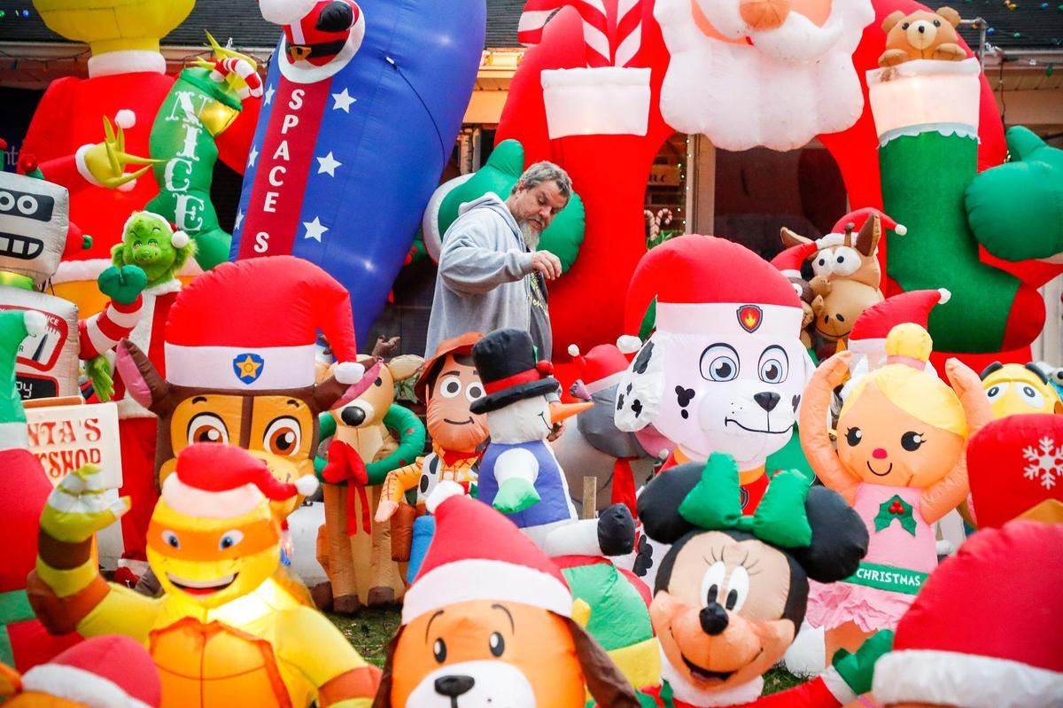 Johnny Richie walks among dozens of inflatable characters in front of his home at 200 Toronto Rd. in Lexington, Sunday, Nov. 29. The Richie family has been decorating their yard for Christmas for at lead 15 years and encourage people to walk through the display.