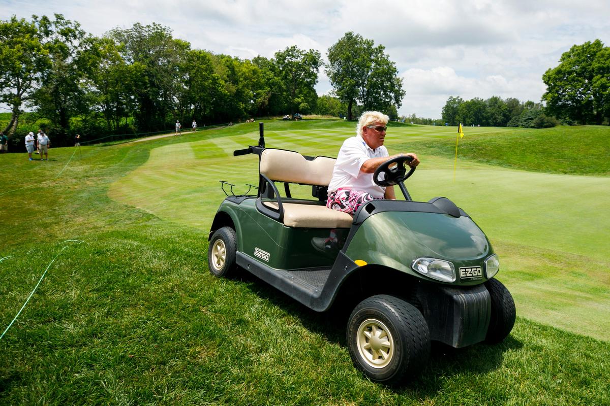 John Daly uses a golf cart to navigate around the 16th green during Thursday’s opening round.