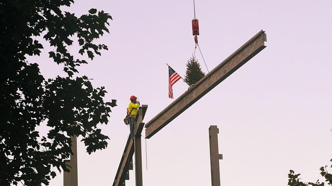 Construction workers at Keeneland raise a beam, along with a tree and an American flag, into place as part of the ongoing construction of a new Paddock Building at Keeneland Race Course on Oct. 4, 2024, in Lexington.