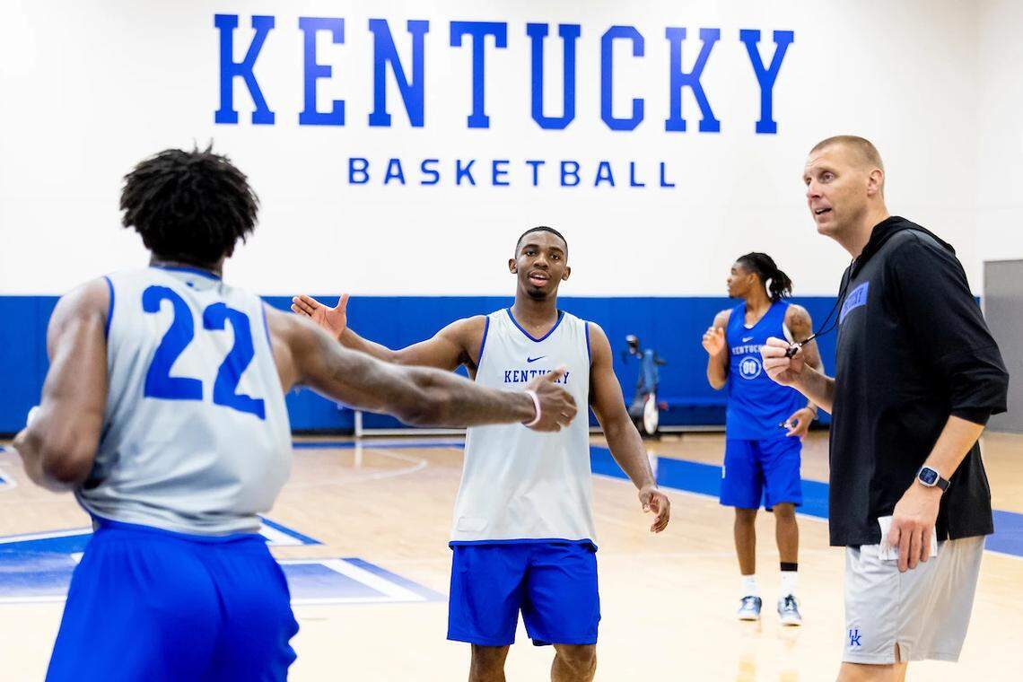 Lamont Butler, center, slaps hands with teammate Amari Williams as UK basketball coach Mark Pope looks on during Monday’s practice at the Joe Craft Center.