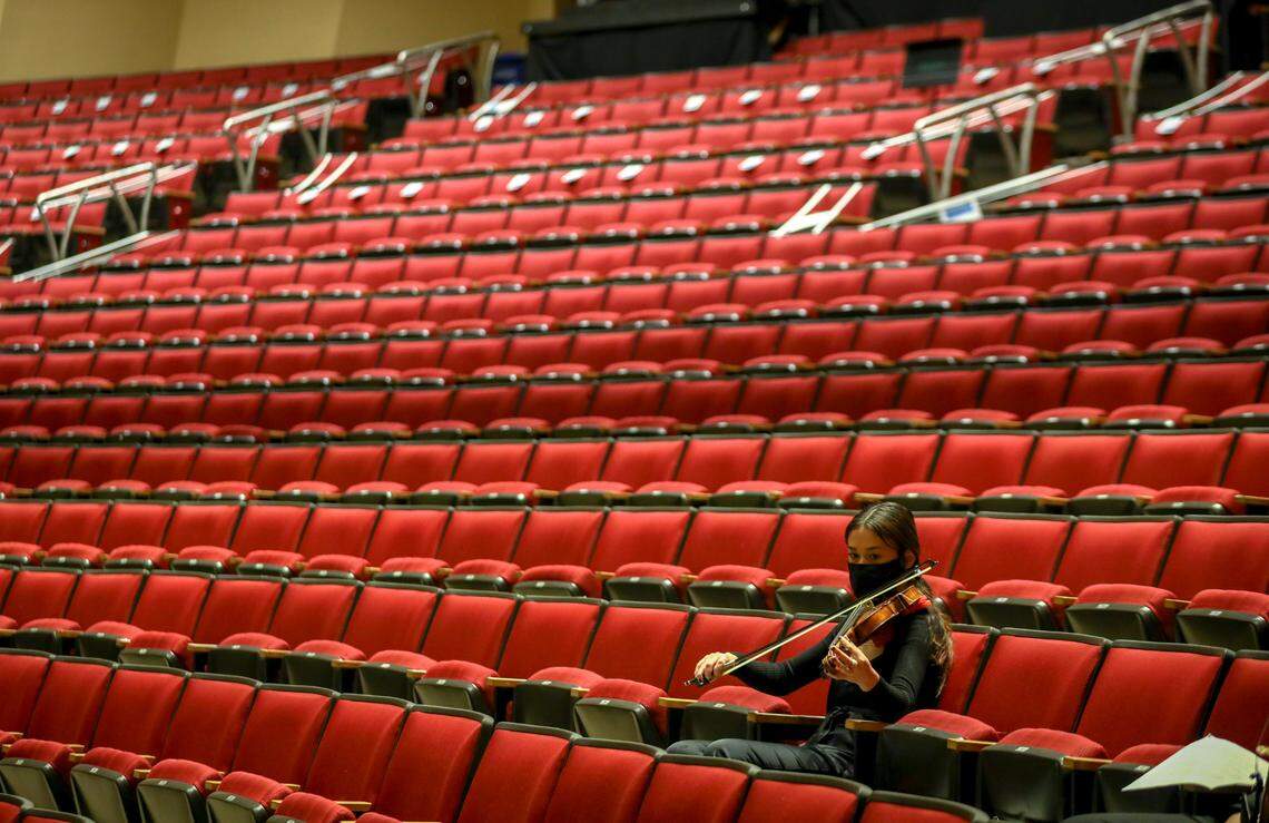 A student prepares their violin surrounded by empty seats before a performance that will be recorded for distribution online at the University of Kentucky in Lexington, Ky., Thursday, October 1, 2020. To take the place of the live performances, staff at the Singletary Center have started an interdepartmental program to record music for people to enjoy online.
