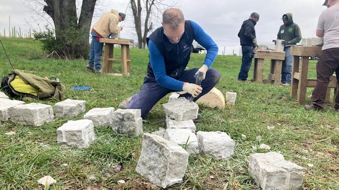 Seth Thomas, an instructor at the Dry Stone Conservancy, shapes limestone during a workshop in Jessamine County on Nov. 23, 2024.