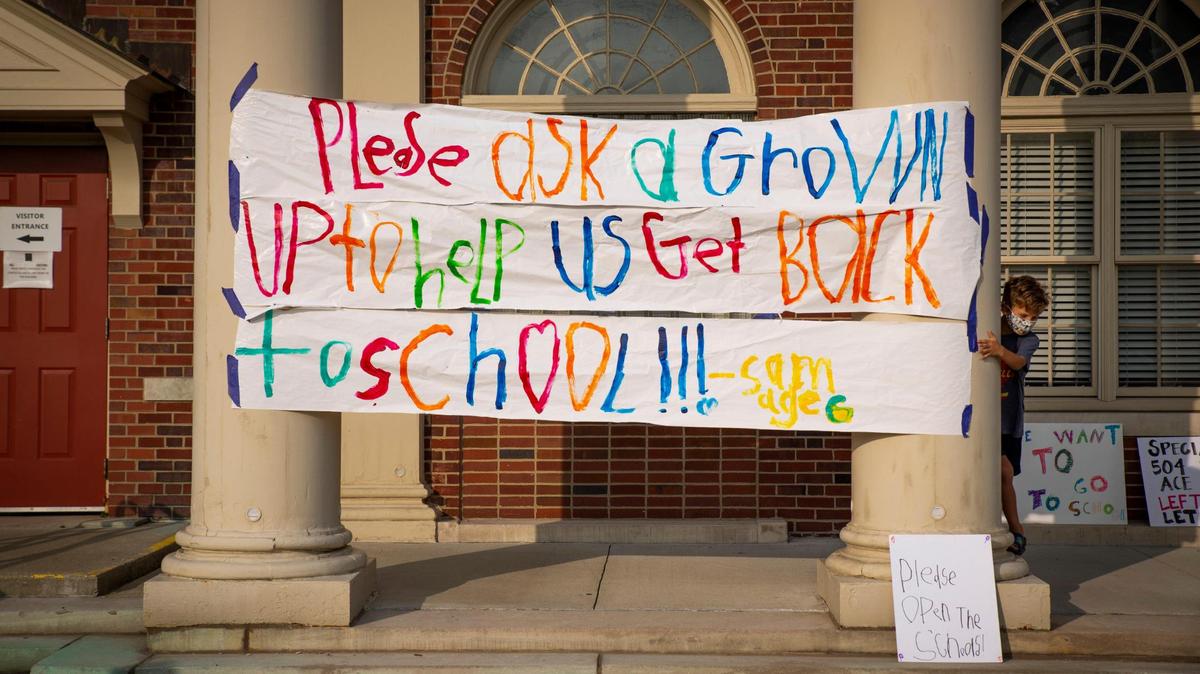 Sam Griffith, a 6-year-old from Maxwell Elementary, stands next to a sign he created during the Let Them Learn rally and protest outside the Fayette County Public Schools central office in Lexington, Ky, on Monday, September 14, 2020.