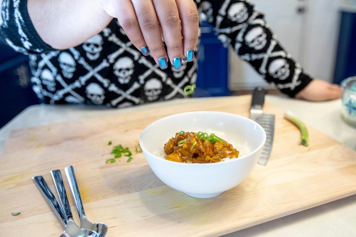 Samantha Fore tops a mango curry with green onion. She’s working on many new projects.