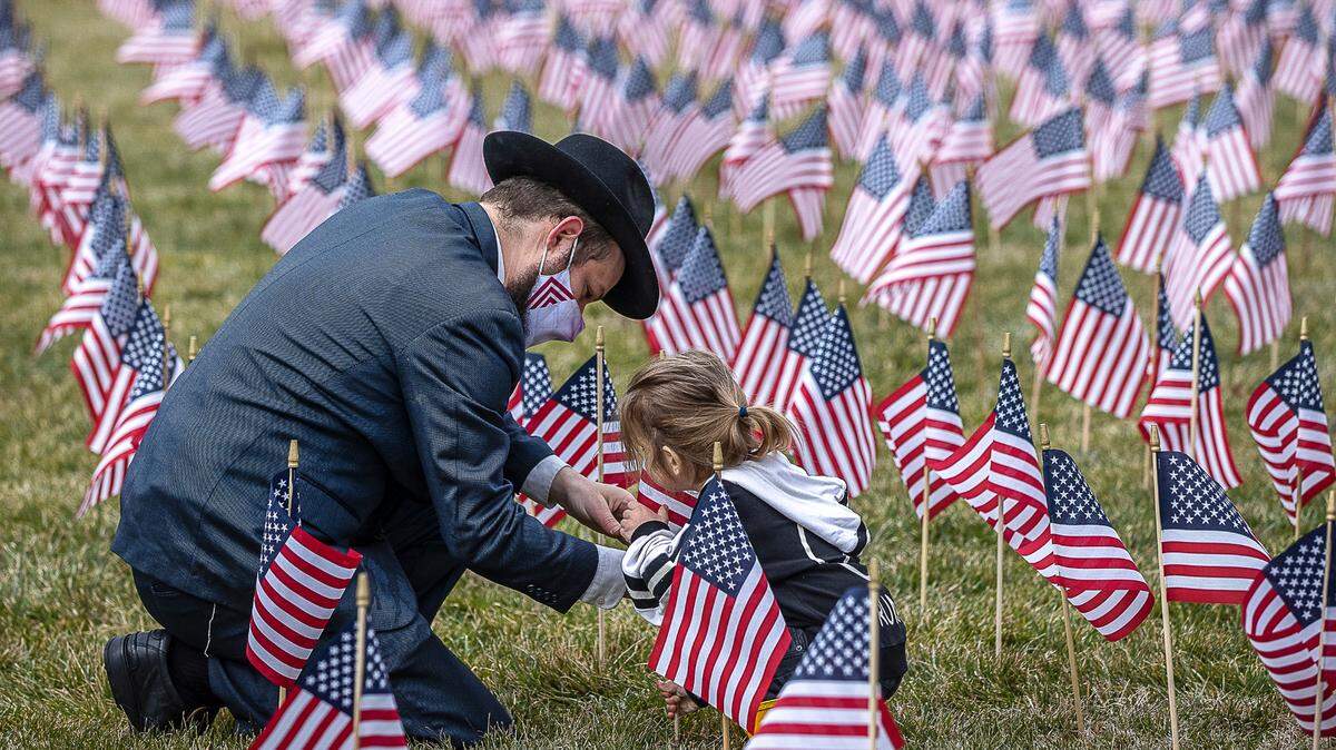 Rabbi Shlomo Litvin, Chabad of the Bluegrass director, and his son, Kehos, 2, both of Lexington, place flags on the back lawn of the Kentucky state Capitol in honor of Kentuckians who have died from complications from COVID-19. The flag memorial, which was first erected two weeks ago, is expanded each week. There are now more than 3,800 flags – representing more than 3,800 deaths.