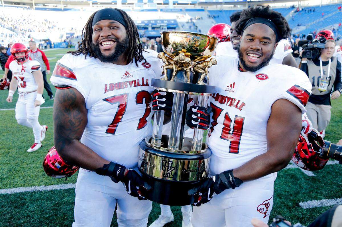 Louisville offensive linemen Lukayus McNeil (72) and offensive lineman Geron Christian carry the Governor’s Cup trophy after the Cardinals defeated Kentucky 44-17 at Kroger Field in 2017. U of L has not claimed the trophy that goes annually to the winner of the UK-Louisville game since.