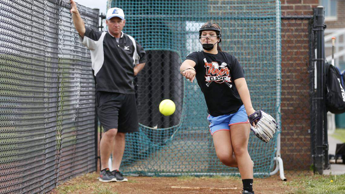 Haylee Hamm, wearing her protective face mask, pitched as her dad and coach, Tom Hamm, watched. Haylee had resisted the idea of a mask before her injury.