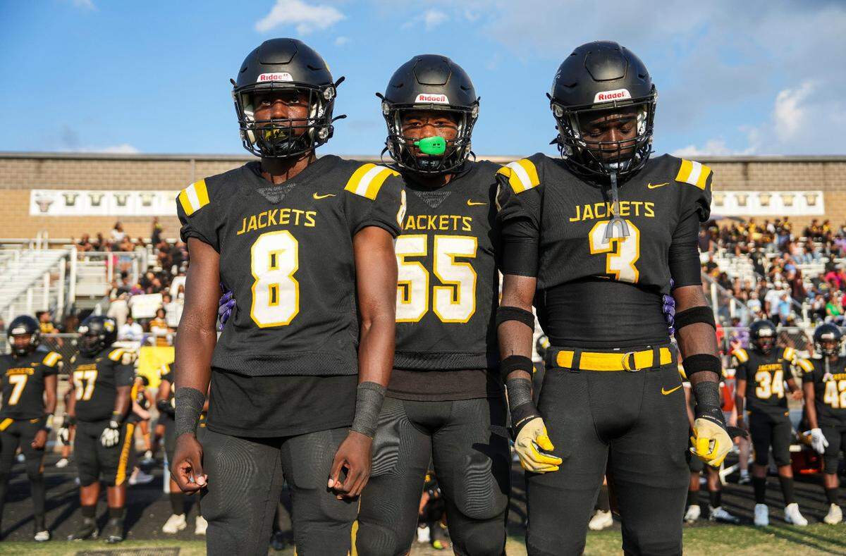 Central's Cortez Stone (8), Central's George Black (55) and Central's Avalon Johnson-McNeal prepare to go to midfield for the coin toss against visiting duPont Manual at Ty Scroggins Stadium Friday night in Louisville. August 23, 2024