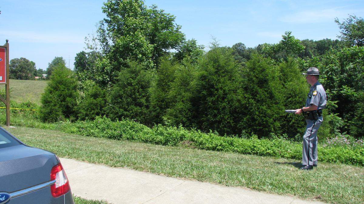 A state police officer stood overlooking the spot where a 31-year-old Russell County woman's body was found Thursday. Sarah Hart was found in the wooded area in the photo. 6/14/2012 photo by Bill Estep