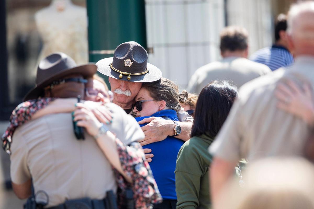 Members of the Scott County Sheriff’s Department are comforted by friends and family following a police escort for deputy Caleb Conley through downtown Georgetown, Ky. The escort for Conley, who was shot the day before, was headed to a funeral home in Cynthiana on Tuesday, May 23, 2023.