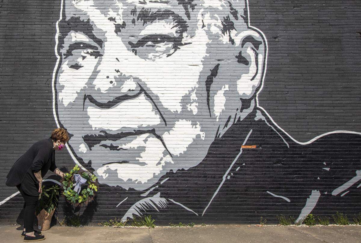 Maribeth Schmitt, of Lexington, Ky., places a wreath below a mural of singer John Prine, on the side of Apollo’s Pizza on Leestown Road in Lexington, on Wednesday, April 8, 2020. Prine, 73, died Tuesday at NashvilleÕs Vanderbilt University Medical Center following complications brought on by COVID-19. The mural was painted by Graham Allen of SquarePegs Studio and Design.