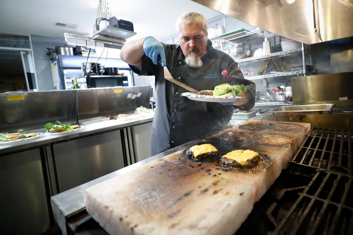 Head chef Jerome Adams prepares a cheeseburger on salt blocks at Waterfront Grille & Gathering. Most menu items will be cooked on the salt blocks.