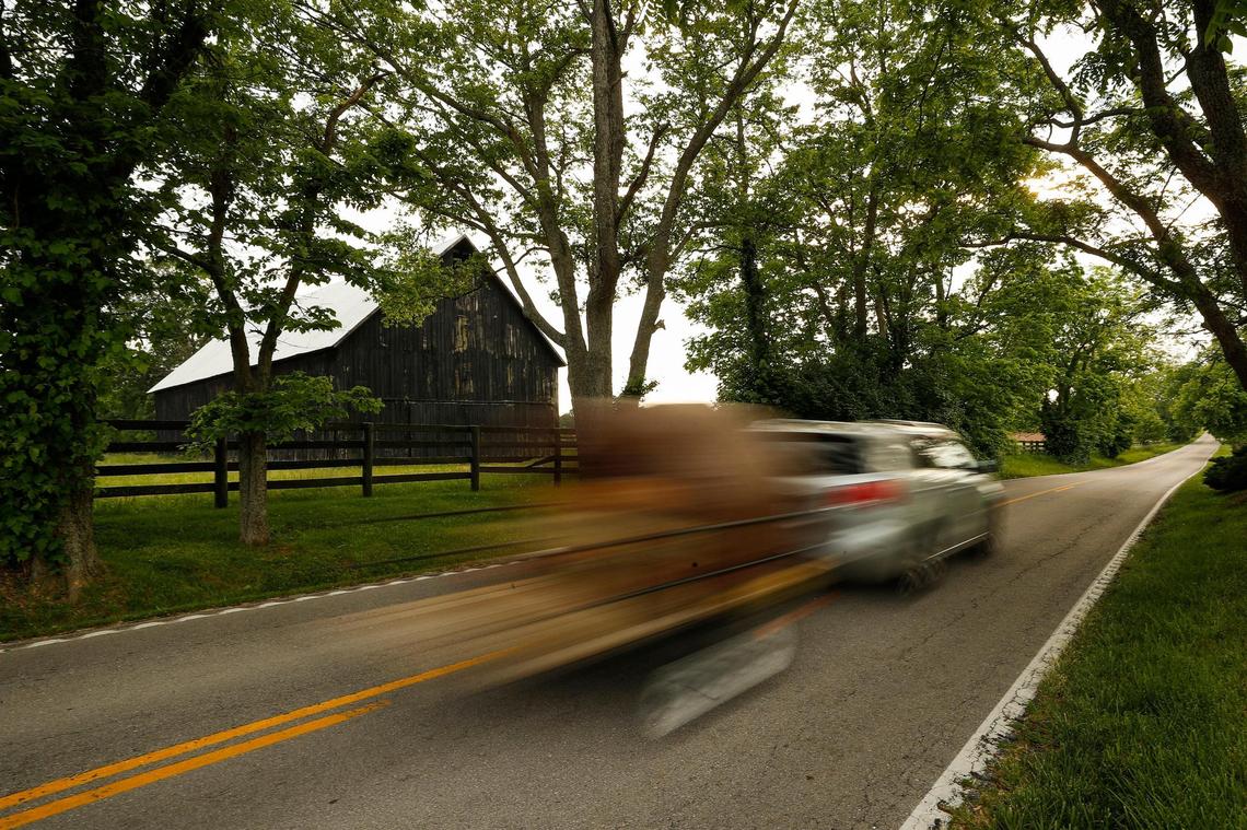 A motorist streaks past a barn adjacent to Old Frankfort Pike Tuesday in Woodford County. Old Frankfort Pike runs 15.5 miles, running from the Distillery District near downtown Lexington to near the intersection of US 60 and I-64.