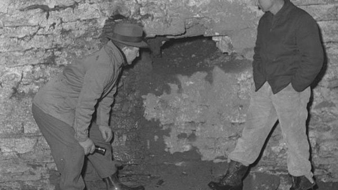 Deputy Sheriff Bill Moss, left, and Burch Peel inspected the entrance to a tunnel dug into the foundation of the bank so burglars could gain access and set off one and maybe two explosions.