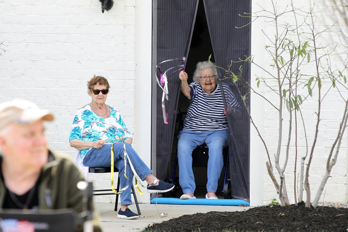 Flo Imig, left, watched as Gen van Buskirk waved a streamer while members of Immanuel Baptist Church staged a drive by parade Friday for residents of Highgrove at Tates Creek senior living community.
