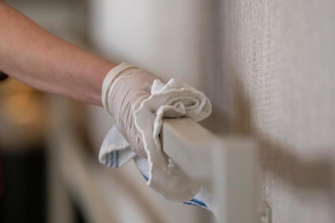 Emily Morrow uses sanitizer Friday to clean a handrail at Epping’s on Eastside.