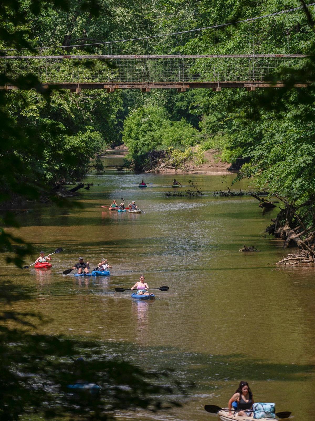 People kayak in the Red River near the Sheltowee Trace Suspension Bridge in the Daniel Boone National Forest near Slade, Ky., on Monday, May 30, 2022.