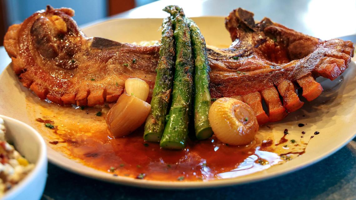 The Khan Khan Pork Chop ($42) at Azur Restaurant and Patio, shown Monday, May 20, 2025 in Lexington, Ky. has three cuts of pork in one: pork belly, pork loin and back ribs. The crispy fried Puerto Rican-style, bone-in, Harrison Farms pork is served over Tasso ham risotto with braised cippolini onion and sautéed asparagus. The dish is finished with a blood orange balsamic gastrique.