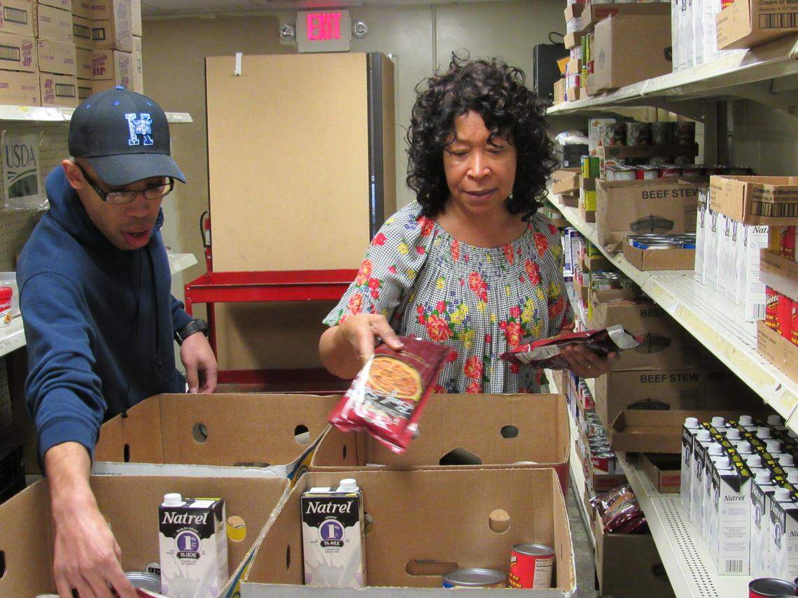 Micah Cunningham, left, and his mother, Amanda Cunningham, volunteer to pack boxes of food on March 23, 2020 to be given away at God’s Food Pantry in Somerset, Ky.