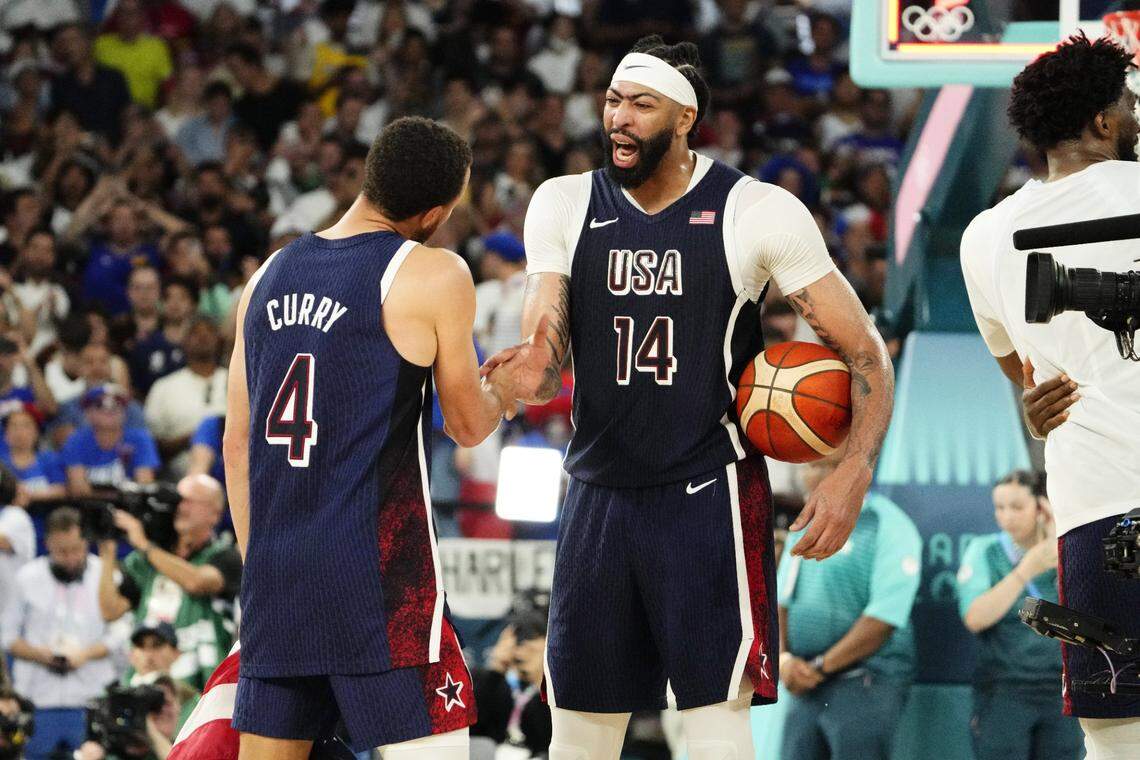 Aug 10, 2024; Paris, France; United States centre Anthony Davis (14) and shooting guard Stephen Curry (4) celebrate after defeating France in the men's basketball gold medal game during the Paris 2024 Olympic Summer Games at Accor Arena. Mandatory Credit: Rob Schumacher-USA TODAY Sports