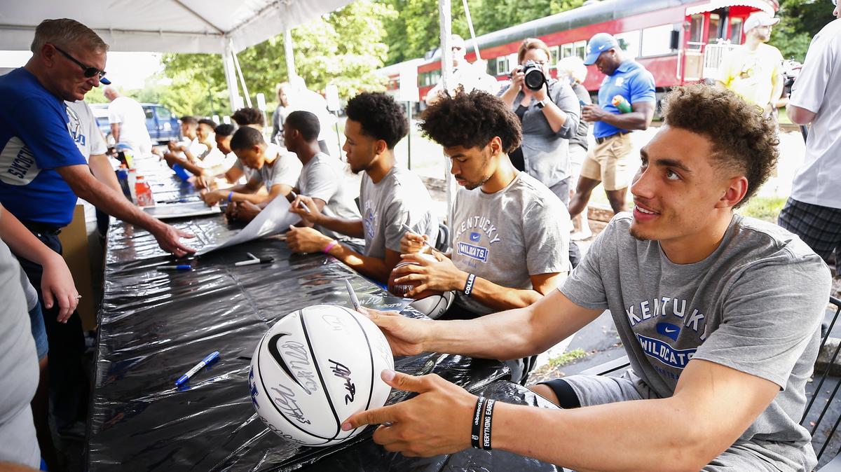 University of Kentucky forward Reid Travis, right, and other members of the team signed basketballs and other items for fans during a train stop as part of the Big Blue Caravan Sunday in Midway.