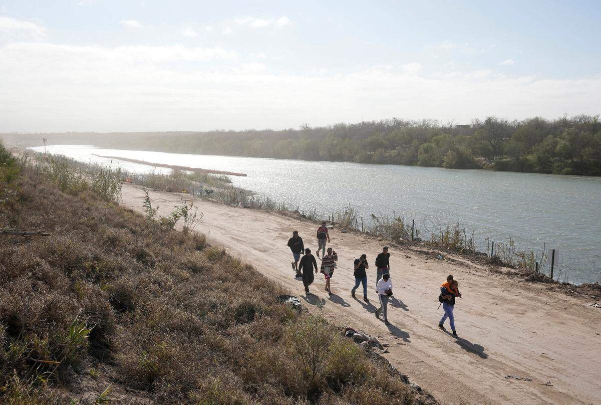 A group of migrants from Venezuela walk along the banks of the Rio Grande to surrender to U.S. Border Patrol after they entered Texas at Eagle Pass on Monday, Jan. 8, 2024.