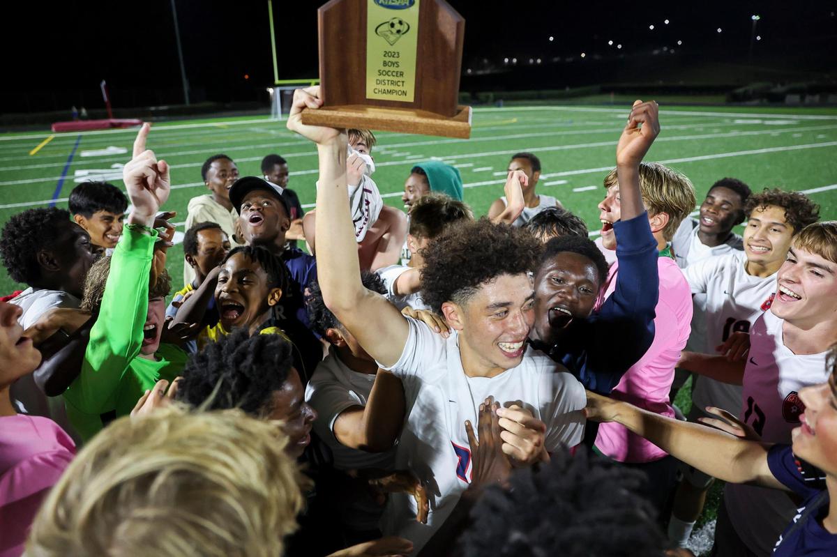 Lafayette senior Sawyer Trowel holds up the 43rd District boys soccer championship trophy as he celebrates with teammates after the Generals defeated Paul Laurence Dunbar in overtime at Tates Creek High School last fall.