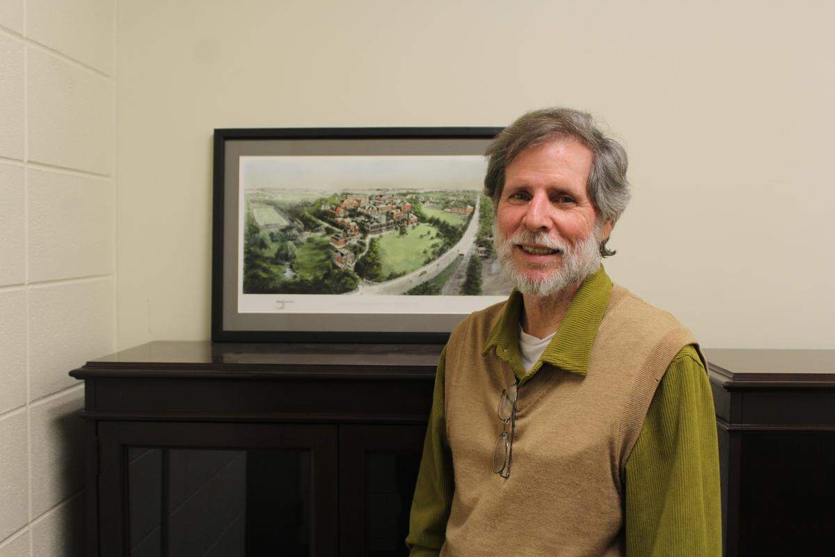 Davy Jones, a toxicology and cancer biology professor emeritus at the University of Kentucky, stands in front of a 1910 rendering of the university, in his office on May 1, 2026, in UK’s Multidisciplinary Science Building.