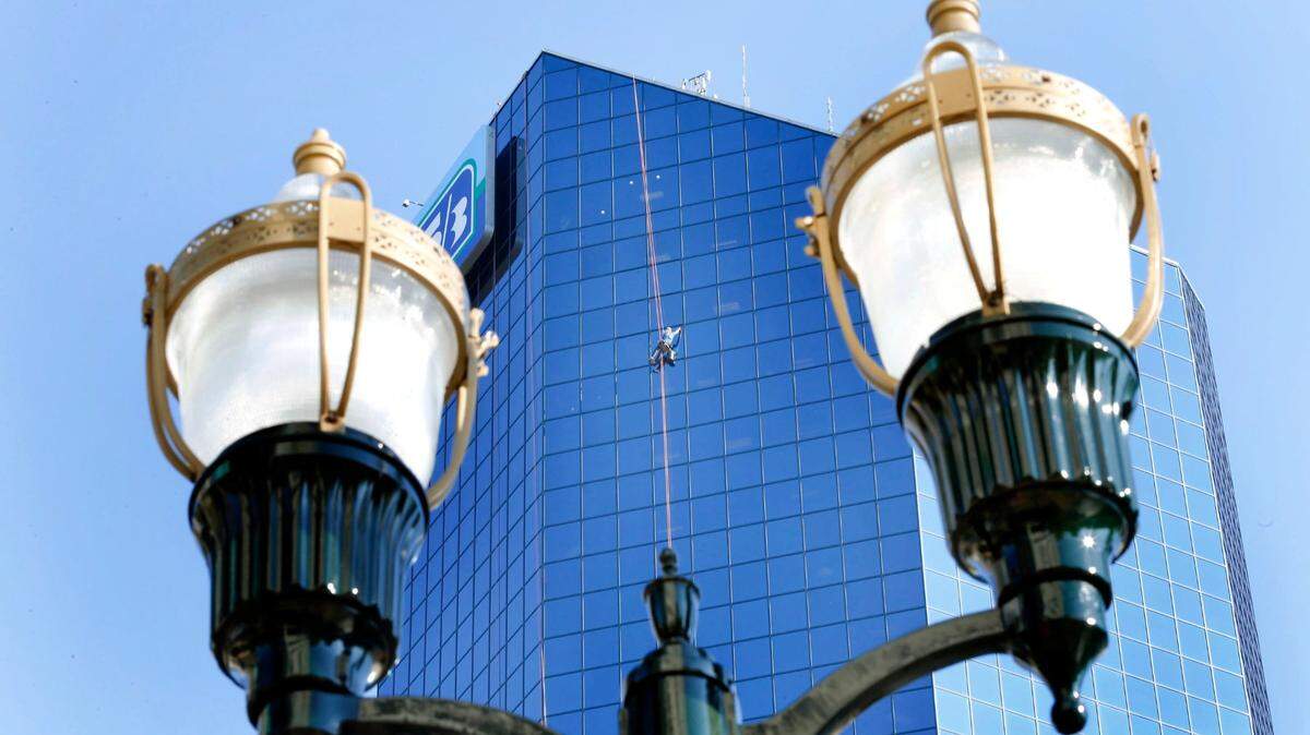 As seen from between two streets lights, Cliff Kennedy, who has washed windows on tall buildings for 23 years, washed the windows on the West Vine St. side of the Lexington Financial Center at 250 West Main St. in Lexington, Ky., Monday, August 24, 2015.