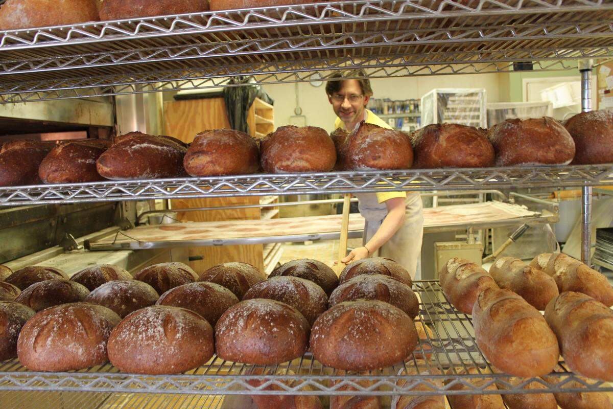 Jim Betts with some of his artisan loaves in 2011 when the bakery was celebrating its 20th anniversary. In college, he says, “I fell in love with breadmaking.” Now he and wife, Francine, are retiring after 35 years and handing the bakery to new owners who will be announced soon.   