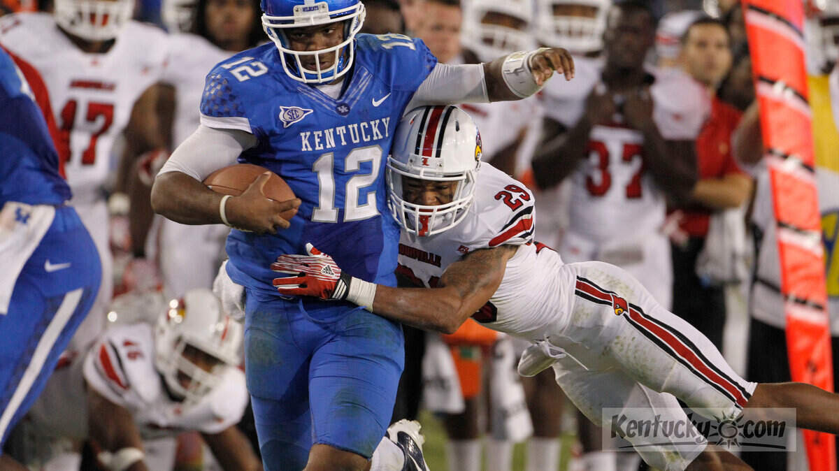 Kentucky Wildcats quarterback Morgan Newton (12) made a first down on this run with about 1:34 left in the game during the University of Kentucky vs. University of Louisville football game on Saturday, Sept. 17, 2011 at Commonwealth Stadium in Lexington.  Louisville Cardinals safety Hakeem Smith (29) couldn't hang on for a tackle.