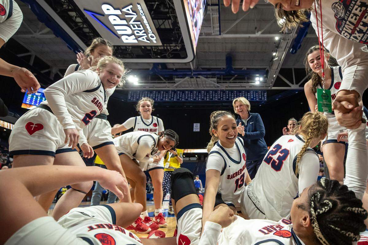 Sacred Heart Academy players celebrate the school’s third consecutive Kentucky girls’ high school basketball state championship after defeating McCracken County 68-53 to win the title Saturday night in Rupp Arena