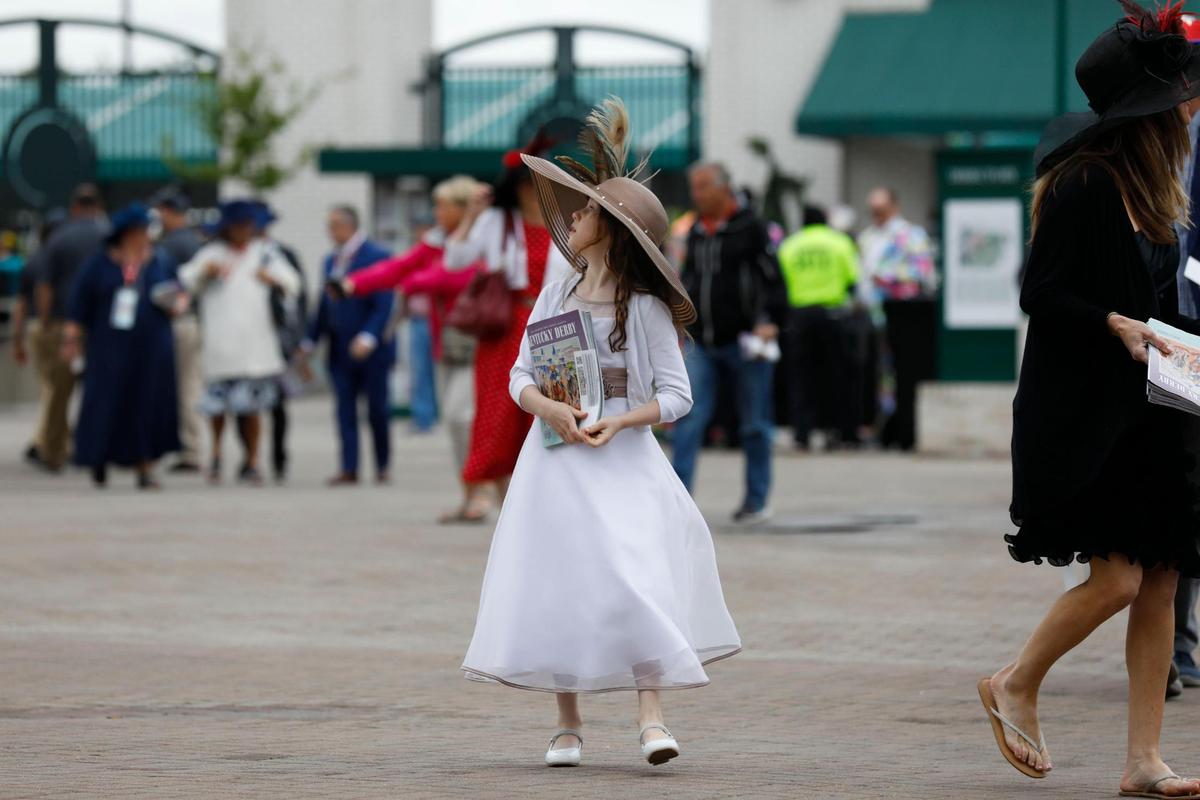 Alivia McSherry, 9, looks around as she enters Churchill Downs in Louisville, Ky., Saturday, May 7, 2022. She wore a couture dress and a hat made by her grandmother for her first derby.