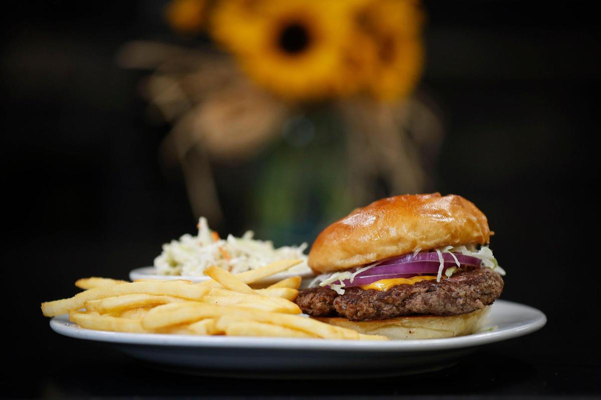 The hand pattied 6oz burger made with fresh ground chuck, lettuce, tomatoes, onions, cheddar cheese and mayonnaise served with french fries and coleslaw at The Cattle Drive restaurant at Lexington’s Blue Grass Stockyards.