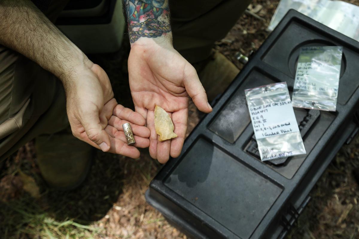 Dr. Jon Endonino holds a bullet casing in his right hand and an arrow head in his left- demonstrating the variety of objects found during a dig in eastern Kentucky.