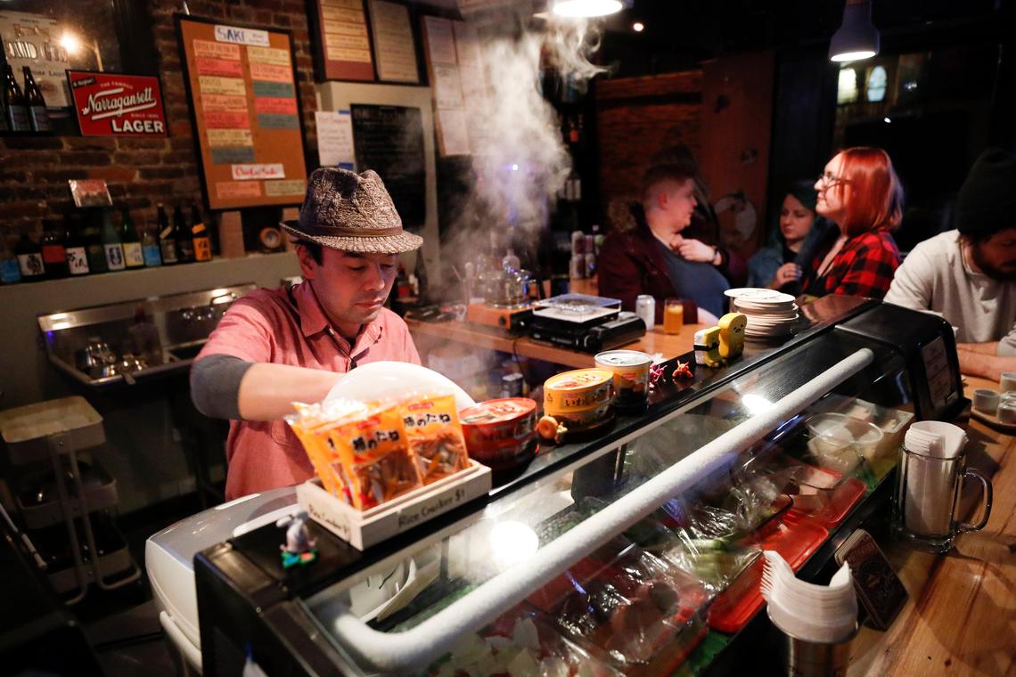 Hidenori Yamaguchi prepares plates for customers Feb. 29 at Standing Room Only. Yamaguchi would prefer customers focus mainly on the drinks they offer and not the food, which is a limited offering.