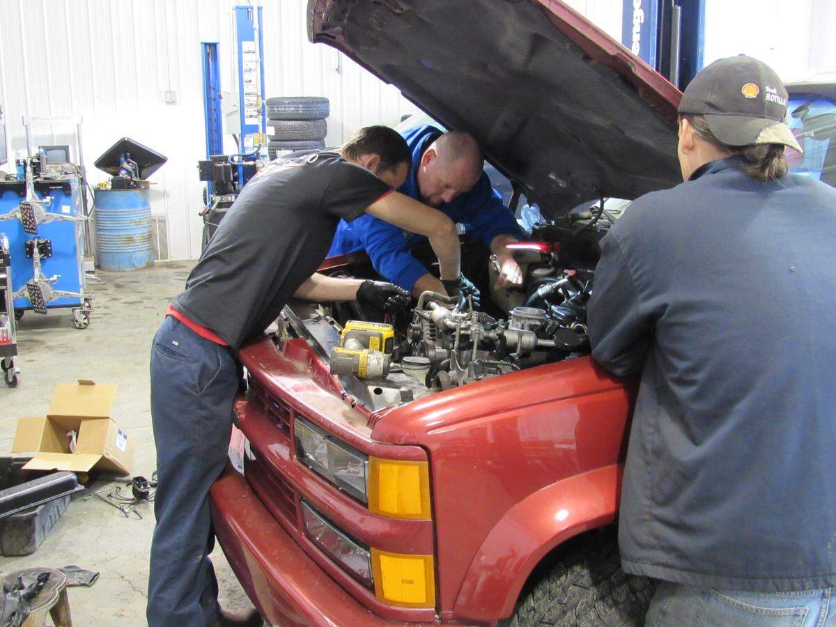 James Keeton, at rear, manager of Second Chance Auto in Louisa, Ky., helps Michael Newsome, left, work on a vehicle at the shop as Rafael Gonzalez, who is training to be a mechanic, observes. The shop provides training for recovering addicts. Newsome was not a client of the program.