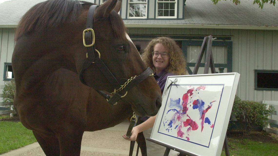 
       Cigar admired the painting he created for a Rerun Fundraiser at the Kentucky Horse Park on Sept. 25, 2002.  With Cigar was Tammy Siters, caretaker at the Hall of Champions.