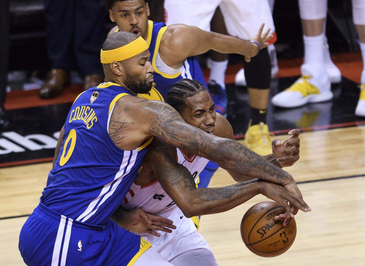 The Warriors’ DeMarcus Cousins (0) tied up the Raptors’ Kawhi Leonard (2) during the second half of Game 2 of the NBA Finals on Sunday.