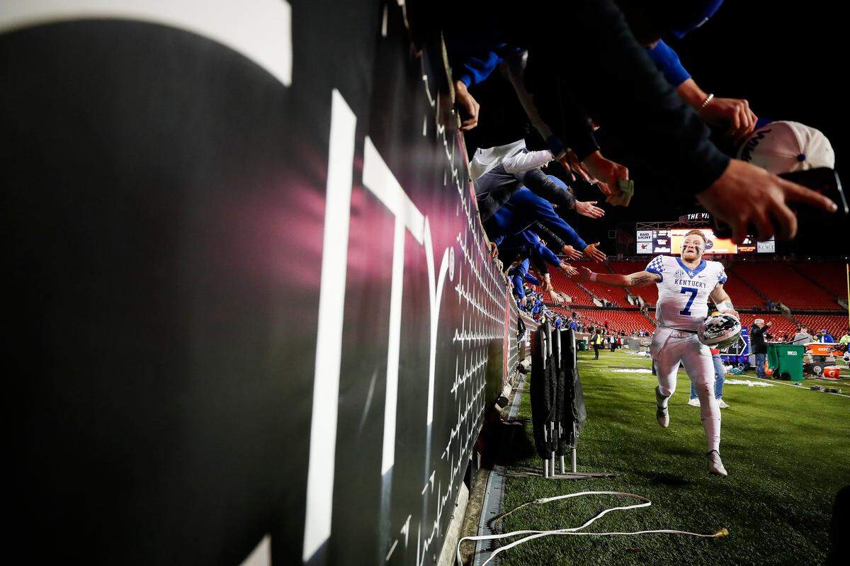 Kentucky quarterback Will Levis (7), who ran for four touchdowns against Louisville, high-fived fans on the way off the field after Saturday night’s 52-21 victory.